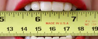 Close up on a woman's teeth biting a measuring tape